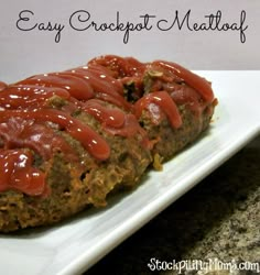 meatloaf covered in ketchup on a white plate with the words easy crockpot meatloaf