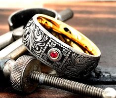 two silver and gold rings sitting next to each other on top of a wooden table