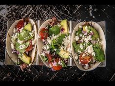 three tacos with avocado, tomatoes, and other toppings on them