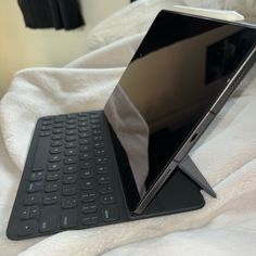 an open laptop computer sitting on top of a white bed covered in sheets and blankets