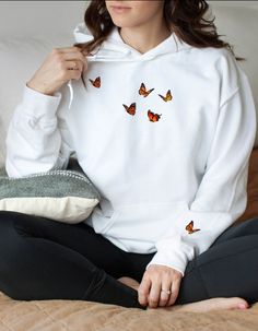 Who knew that the softest hoodie you'll ever own comes with such a cool butterfly design. You won't regret buying this classic streetwear piece of apparel with a convenient pouch pocket and warm hood for chilly evenings. This hoodie is made from PREMIUM fleece so it is super warm without feeling bulky. The butterfly graphic is on the front chest as well as on the wrist! The brand of this hoodie is Cotton Heritage and the style is M2580 * 100% cotton face * 65% ring-spun cotton, 35% polyester * F Hoodie Embroidery Ideas, Hoodie Patches, Hoodie Embroidery, Butterfly Hoodie, Trendy Crewneck, Matching Hoodies, Trendy Hoodies, Designer Sweatshirts, Butterfly Embroidery