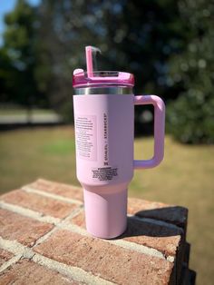 a pink coffee cup sitting on top of a brick wall