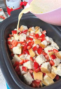 strawberries are being poured into a crock pot filled with breadcrumbs