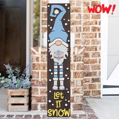 a wooden sign that says let it snow on the front porch next to a potted plant