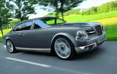 a silver car driving down the road with trees in the background