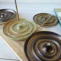 two metal pans sitting on top of a wooden table next to a book and candle holder