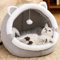 a white cat laying in a grey kitty bed