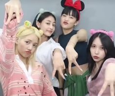 four young women posing for a photo with mickey mouse ears on their head and one pointing at the camera