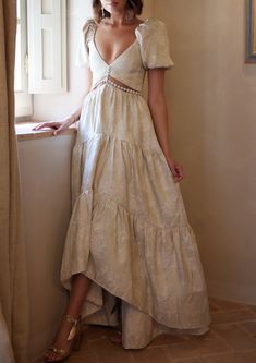 a woman standing next to a window in a white dress