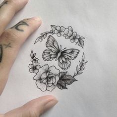 a person's hand holding a piece of paper with flowers and butterflies on it