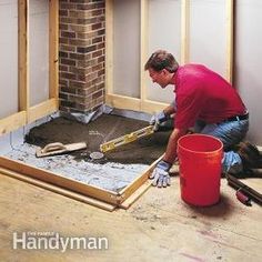 a man is working on the floor in front of a brick fire place with tools