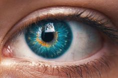 an eye with blue and yellow iris is shown in this close up photo, it appears to be looking at the viewer