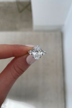 a woman's hand holding an engagement ring with three diamonds on top of it