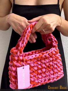 a woman is holding a pink and red bag with a tag on it's handle