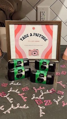 four cameras sitting on top of a table with pink and green confetti around them