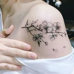 a woman's shoulder tattoo with flowers on the left side of her arm and chest