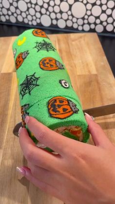 a person holding a knife in front of a green roll with halloween decorations on it