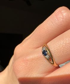 a woman's hand with a ring on it and a blue stone in the middle