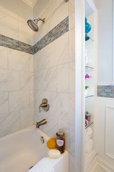 a bathroom with a bathtub, shower head and toilet paper