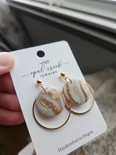 a pair of earrings is shown in front of a card with the tag on it