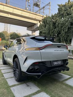 a silver sports car parked in front of a bridge