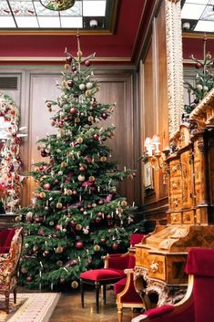 a christmas tree is in the middle of a room with red chairs and other decorations