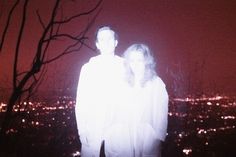 two people standing in front of a city at night