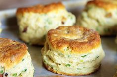 several small biscuits sitting on top of a baking pan covered in cheese and herbs, ready to be eaten