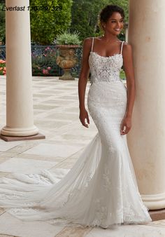 a woman in a white wedding dress standing next to pillars and looking at the camera