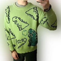 a man in a green sweater taking a selfie with his cell phone