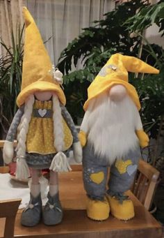 two stuffed gnomes sitting on top of a wooden table