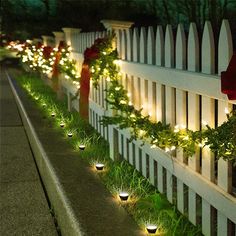 a white picket fence with christmas lights on it