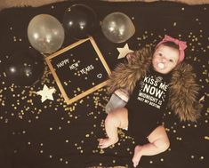 a baby is laying on a blanket with balloons and confetti