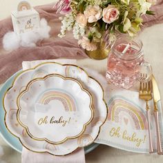 there is a table setting with plates and napkins on it, along with pink flowers