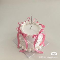 a white cake with pink ribbon on top