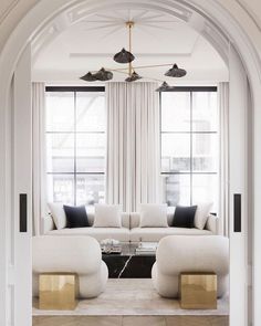 a living room filled with white furniture and windows