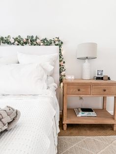 a bed with white sheets and pillows next to a night stand