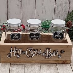 three mason jars are sitting in a wooden box with the words hot cocoa bar on it