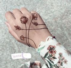 a woman's hand with a flower tattoo on her left wrist and the word henna written in black ink