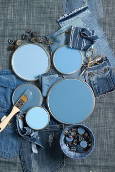 three blue paint cans sitting next to each other on top of denim pants with buttons in them