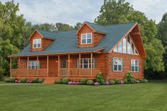 a large log cabin home in the middle of a grassy area with trees and bushes