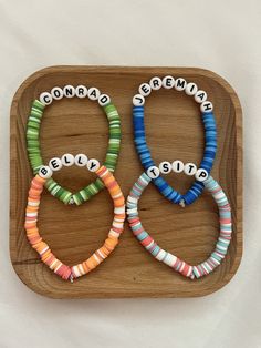 three bracelets with words written on them sitting on a wooden tray next to each other