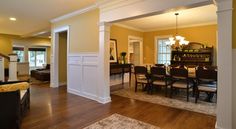 an open living room and dining room area with hardwood floors, yellow walls, and white trim