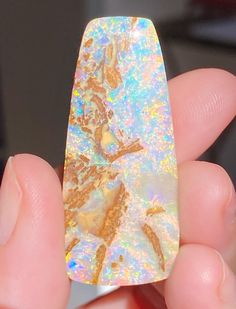 a person holding a piece of opal in their hand