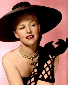 an old photo of a woman wearing a large hat and holding her arm around her waist