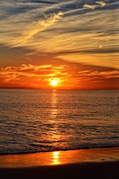 the sun is setting over the ocean with clouds in the sky and on the water