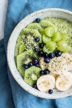 a bowl filled with kiwis, bananas and blueberries on top of a blue towel