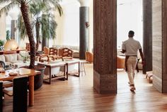 a man is walking through the lobby of a hotel with palm trees in the background