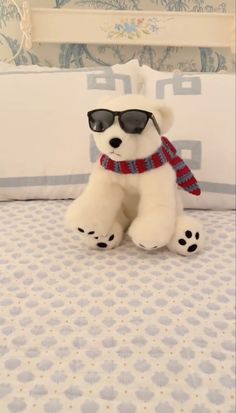 a white teddy bear wearing sunglasses on top of a bed