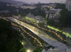 an aerial view of a city at night, with lights on the walkway and buildings in the background